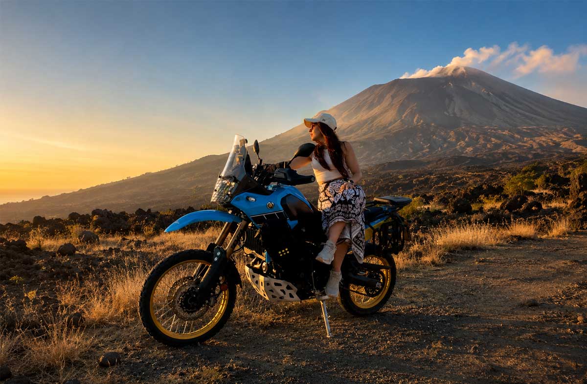 Motociclista con moto adventure durante un tour sull’Etna in Sicilia con il vulcano sullo sfondo