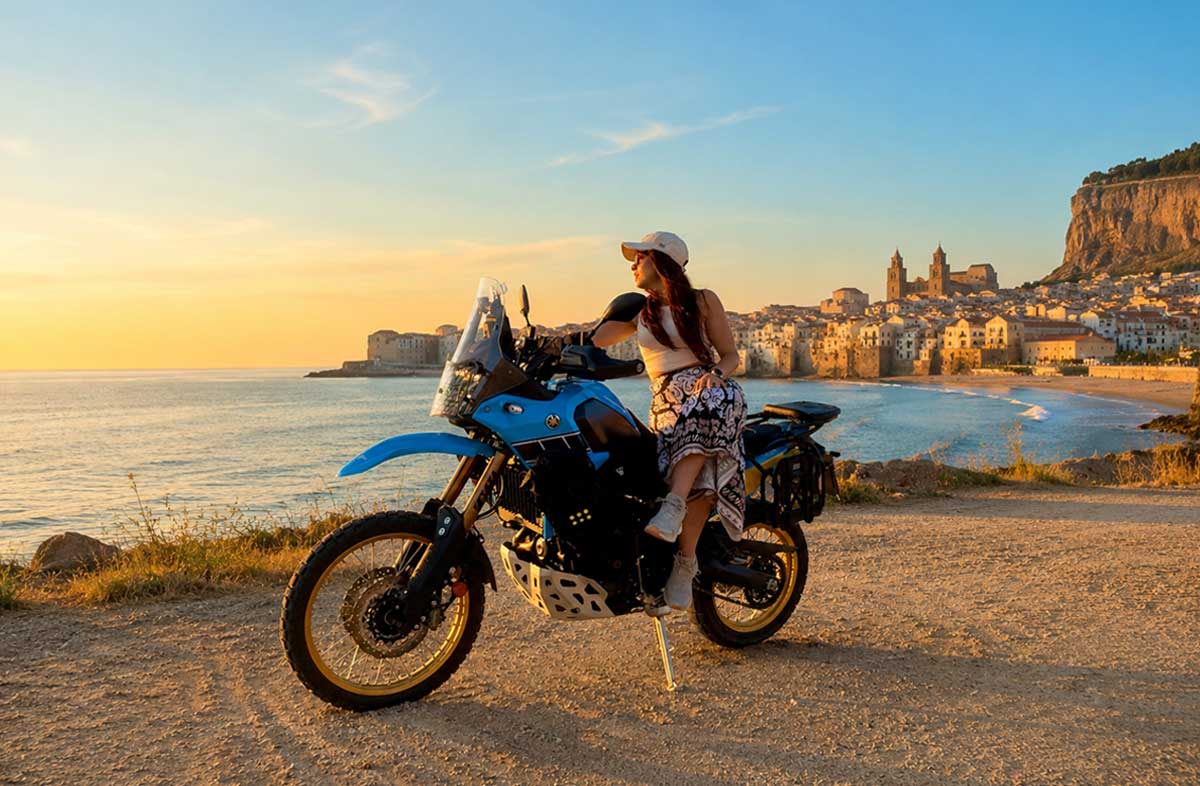 Tour in Moto sull’Etna in Sicilia | Moto Escursioni Motociclista con moto adventure durante un tour in Sicilia con vista su Cefalù e sul mare